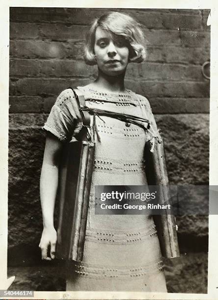 Bootlegger recently arrested in Cincinnati had this novel device strapped around him for carrying his stock of wet goods. Photo shows a young lady...