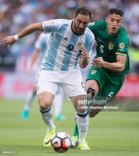 Gonzalo Higuain, of Argentina dribbles the ball as Nelson Cabrera of Bolivia defends during a group D match between Argentina and Bolivia at...