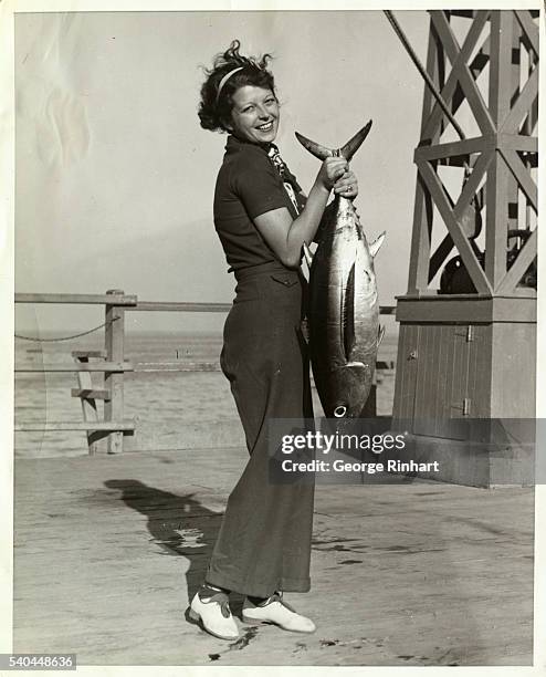 "Hurry up! He's heavy, take that picture quick!" Miss Hermine Sierks, a Pasadena society girl, finds posing for a picture with her Albacore catch...