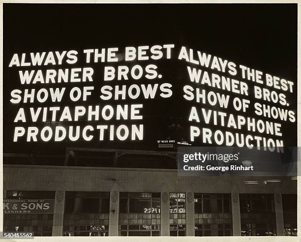 Photo shows lighted billboard advertising Warner Brothers movies. Undated.