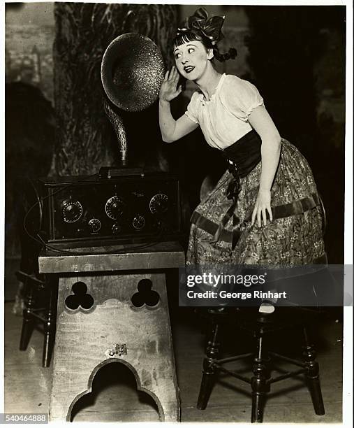 Photo shows Violet Carlson, stage and movie star listening in on the radio, while waiting for her cue to do her comedy stuff in the Student Prince.