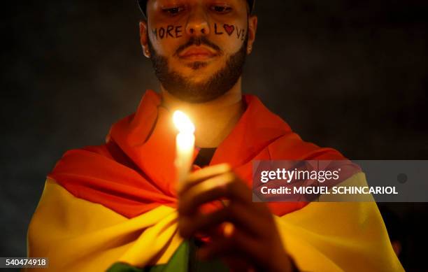 Activists carrying lit candles and flags participate in a vigil to pay tribute to the victims of the massacre occured at a gay club in Orlando, in...