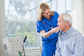 Home healthcare nurse helping elderly man with oxygen