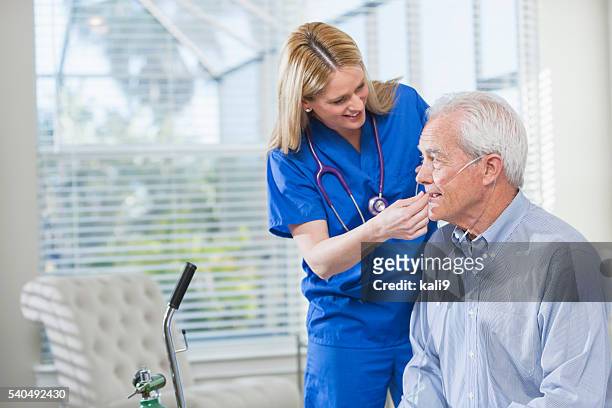 home healthcare nurse helping elderly man with oxygen - medical oxygen equipment 個照片及圖片檔
