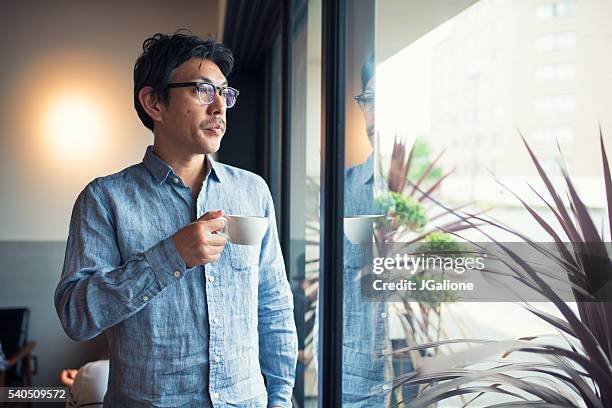 窓から見ているコーヒー カップを保持している男 - man looking away ストックフォトと画像