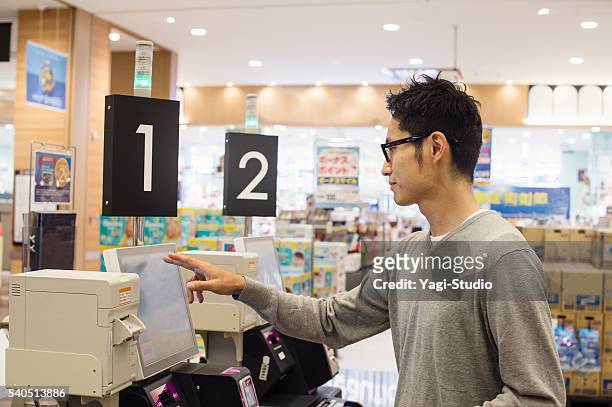 mid adult man using the cash register of self-service - checkout register stock pictures, royalty-free photos & images