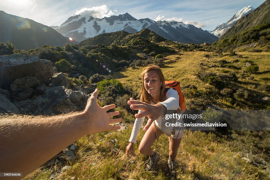 Woman hiking pulls out hand to get assistance from teammate