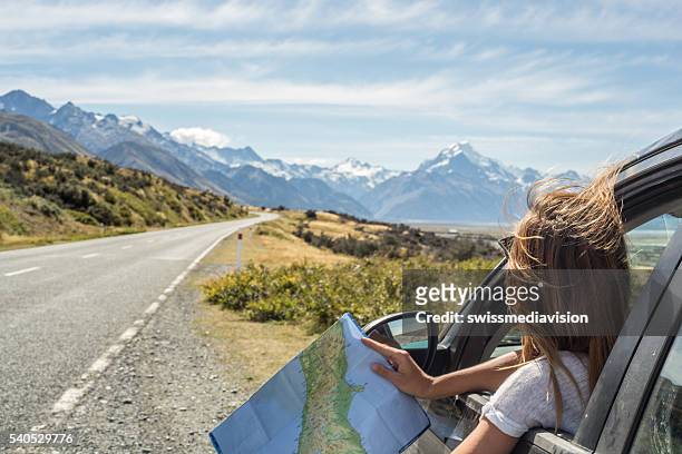 portrait of young woman in car looking at map - reisbestemmingen stockfoto's en -beelden