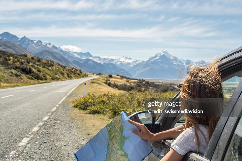Portrait of young woman in car looking at map