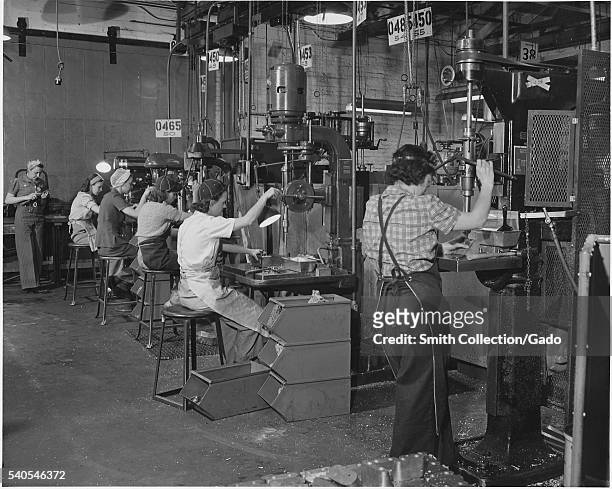 Women man America's machines in a west coast airplane factory, where the swing shift of drill press operators is composed almost entirely of women,...