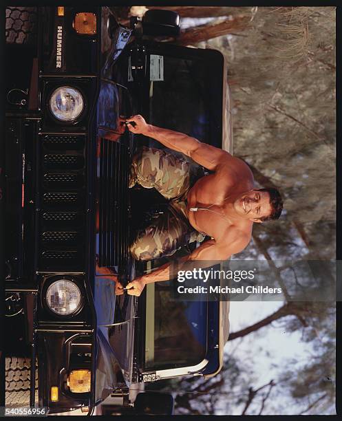 American actor and bodybuilder Christian Boeving kneeling on a hummer.