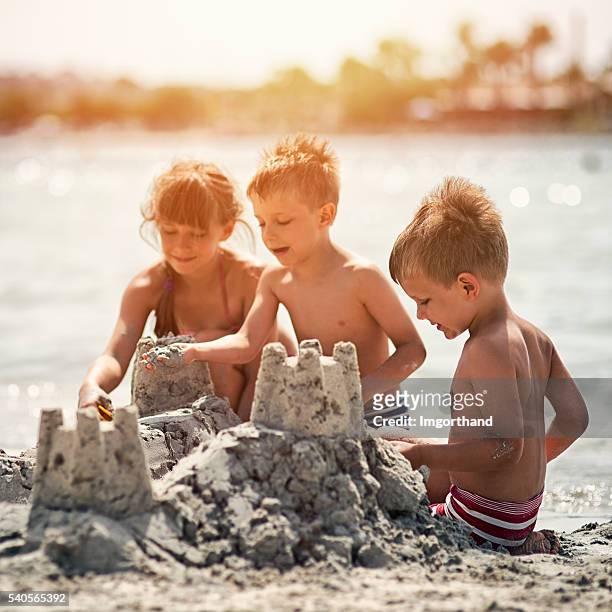 enfants de construire un château de sable sur la plage - château de sable photos et images de collection