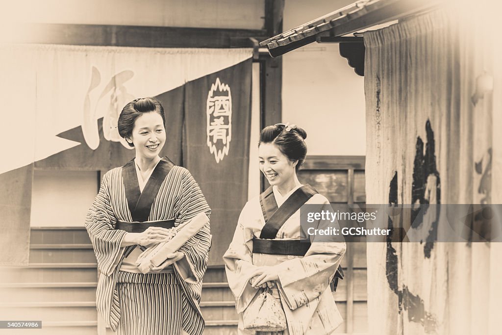Duas mulheres japonesas vestidos Tradicionalmente, falando de um passeio.