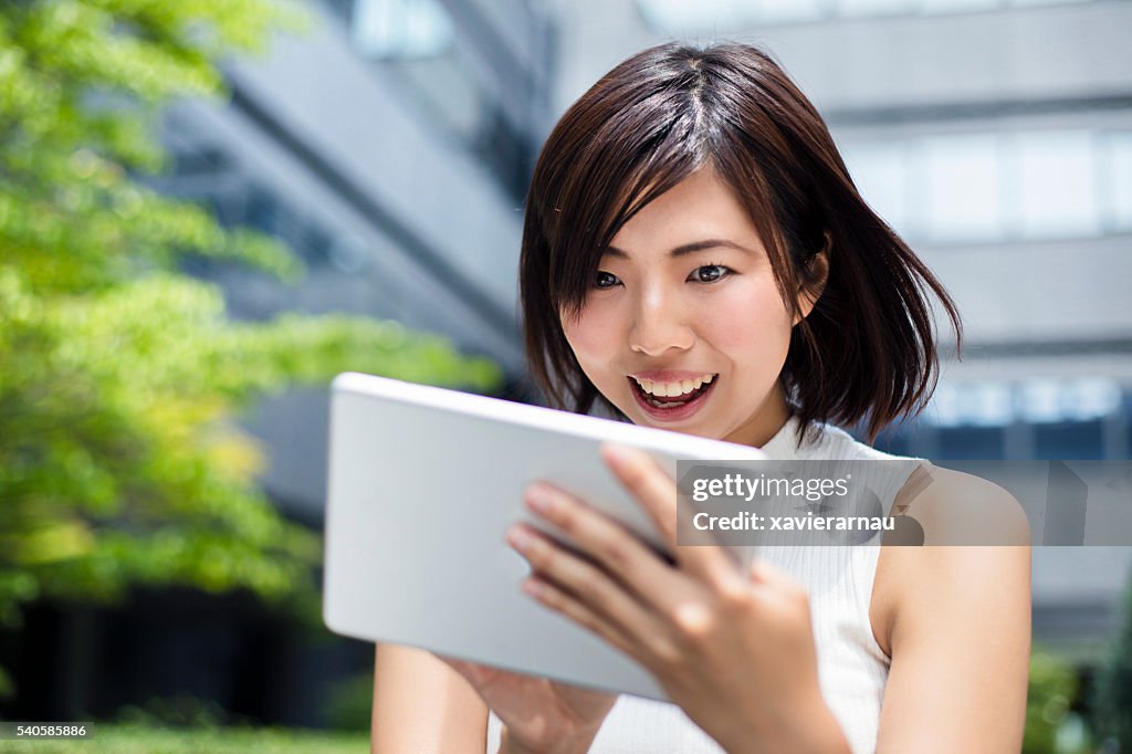 Überrascht japanische Geschäftsfrau schaut an Digitaltablett