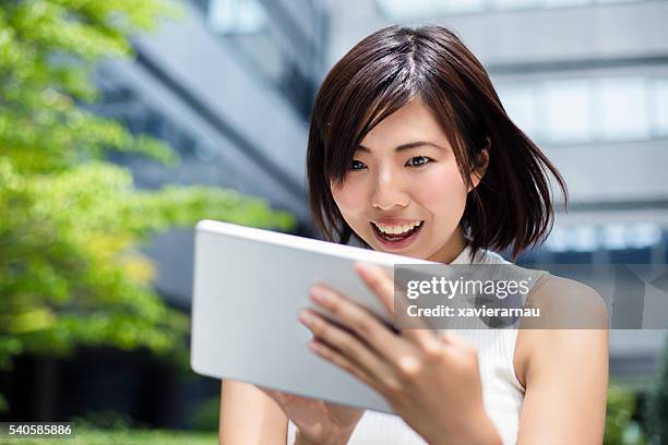 surprised japanese businesswoman looking at digital tablet - surprised woman looking at tablet stock pictures, royalty-free photos & images