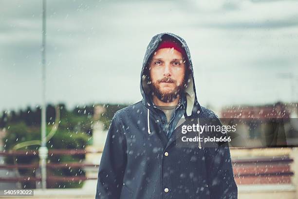 man with raincoat under heavy rain - raincoat stock pictures, royalty-free photos & images