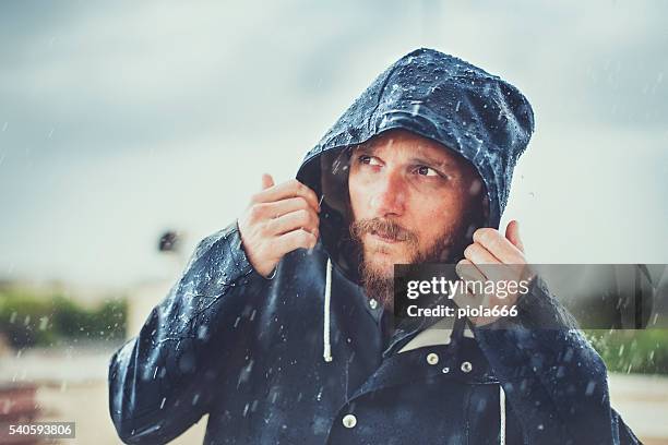 man with raincoat under heavy rain - regnkläder bildbanksfoton och bilder