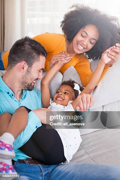 alegre joven familia en casa. - multiracial couple fotografías e imágenes de stock