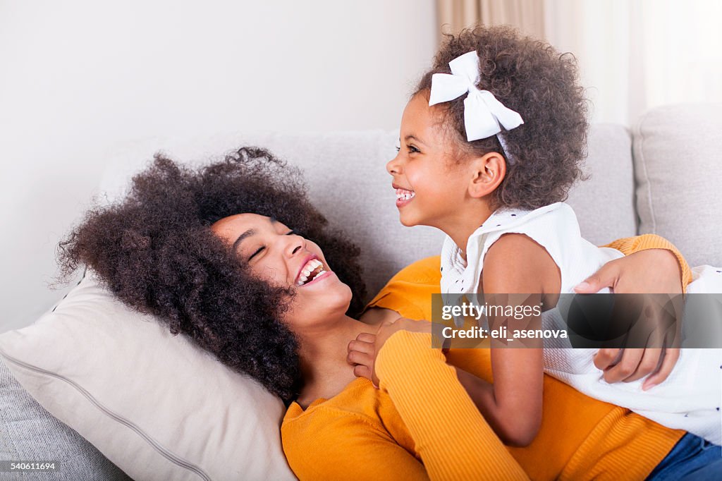 Playful African American mother and daughter having fun at home.