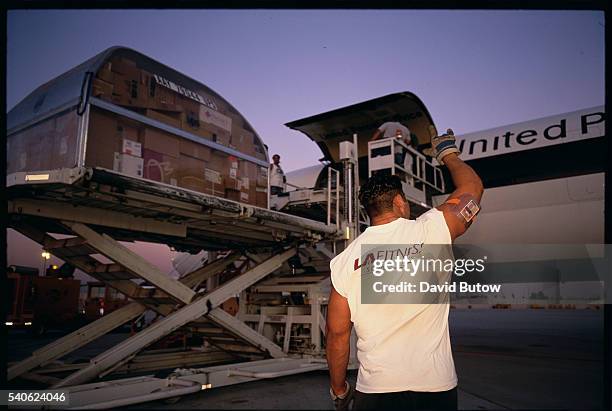 Employee signals to another while the plane is being loaded and unloaded at the company's West Coast Air Hub in Ontario, California.