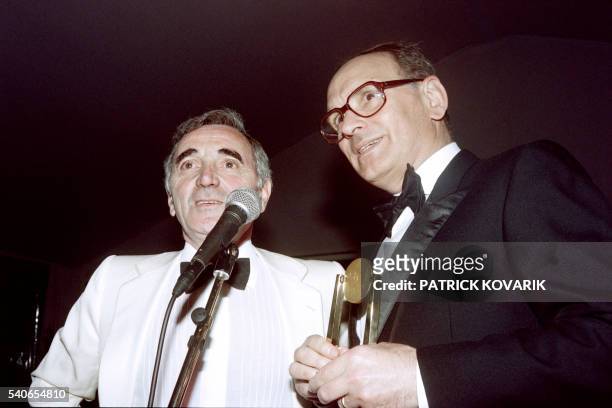 Italian composer Ennio Morricone receives from French singer Charles Aznavour the Sacem music foundation's film score award during the 43th Cannes...