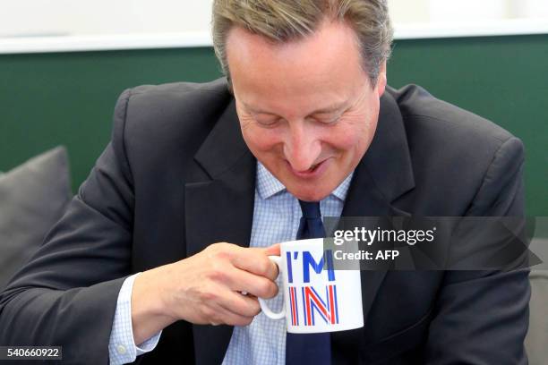 Britain's Prime Minister David Cameron sips from an "I'm In" mug as he meets television presenters Jeremy Clarkson and James May during a visit to W...