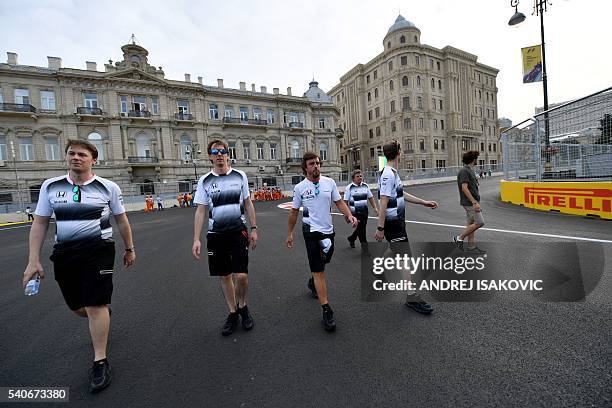 McLaren Honda F1 Team's Spanish driver Fernando Alonso and his team members walk along the track at the Baku City Circuit, on June 16, 2016 in Baku,...