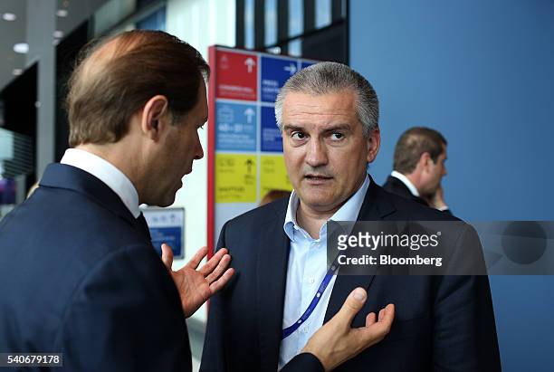 Sergey Aksyonov, prime minister of the autonomous republic of Crimea, right, speaks to a fellow attendee between sessions on the opening day of the...