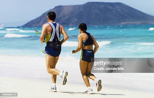 Ein Mann und eine Frau beim Laufen am Strand von Fuerteventura. Sporturlaub; Joggen; Aufgenommen Juli 1999.