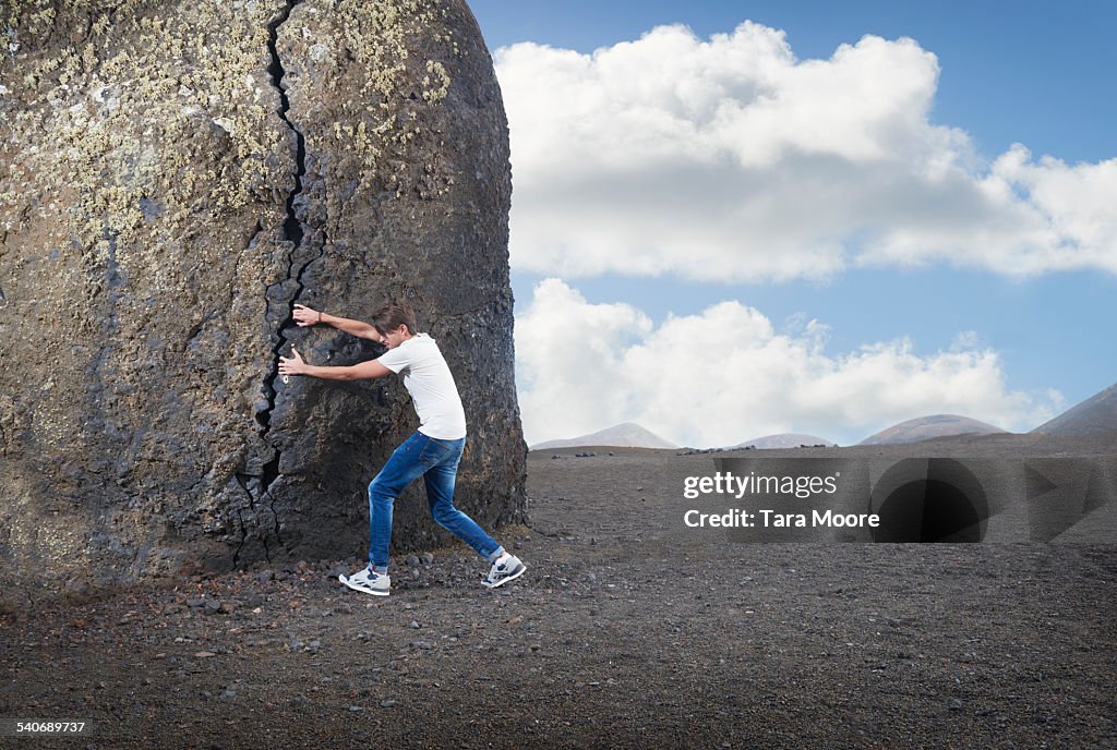 Man pulling apart large rock in desert landscape