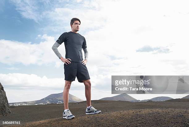 male runner standing in barren landscape - running shoes sky stock-fotos und bilder