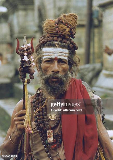 Ein Sadhu in Nepal. Drei weiße Streifen auf der Stirn und ein Dreizack in der Hand weisen den Mann als Anhänger Shivas, dem Gott der Auflösung und...