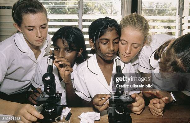 Südafrika: Eine Gruppe Schülerinnen einer High School in Durban hat sich im Unterricht um zwei Mikroskope versammelt. Die Mädchen tragen Schuluniform...