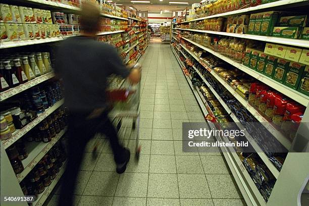 Mann mit Einkaufswagen zwischen Regalen im Supermarkt. .