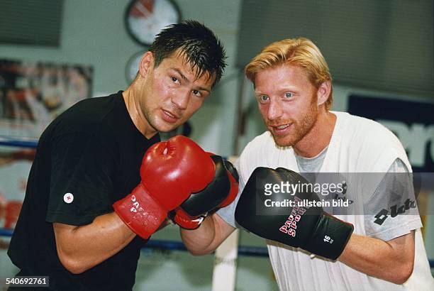 Der Boxer Dariusz Michalczewski steht zusammen mit dem Tennisspieler Boris Becker in Boxerpose. Beide tragen Boxhandschuhe. Aufgenommen Juli 1998.