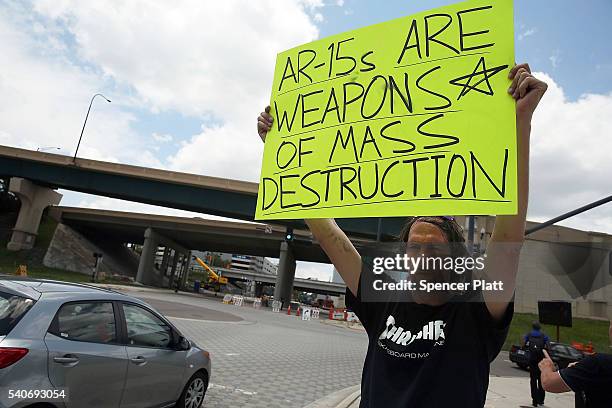 Matthew Fugina holds up a sign against the AR-15 assault rifle down the road from a memorial for those killed at the Pulse nightclub shooting on June...