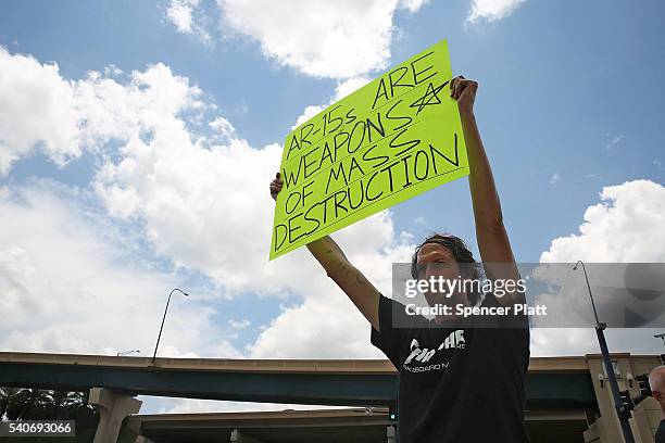 Matthew Fugina holds up a sign against the AR-15 assault rifle down the road from a memorial for those killed at the Pulse nightclub shooting on June...