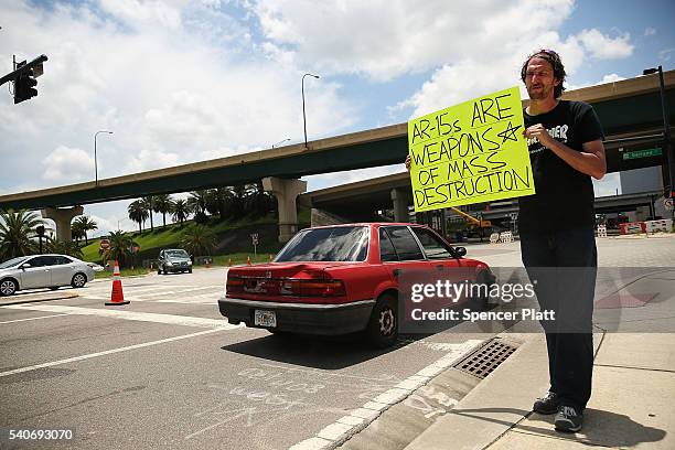 Matthew Fugina holds up a sign against the AR-15 assault rifle down the road from a memorial for those killed at the Pulse nightclub shooting on June...