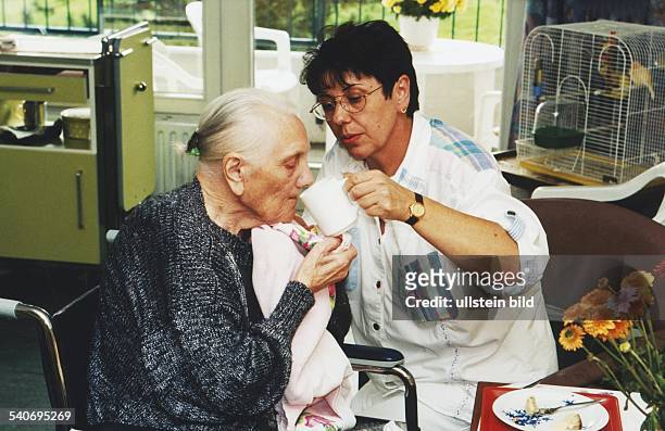 Eine Pflegerin füttert eine alte Frau im Altersheim. .