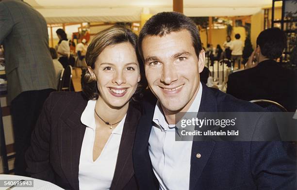 Der deutsche Tennisprofi Carl-Uwe Steeb und seine Ehefrau Kimberly Goy, die eine Halskette mit Perle trägt, sitzen in einem Restaurant. Steeb hat...