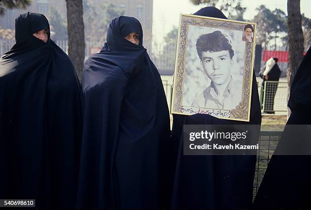 Mother of a young martyr of revolutionary forces killed Iran - Iraq war, holds picture of her son in Behesht-e Zahra cermetry, Tehran.