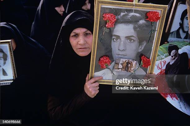 Mother of a young martyr of revolutionary forces killed Iran - Iraq war, holds picture of her son in Behesht-e Zahra ceremony, Tehran.