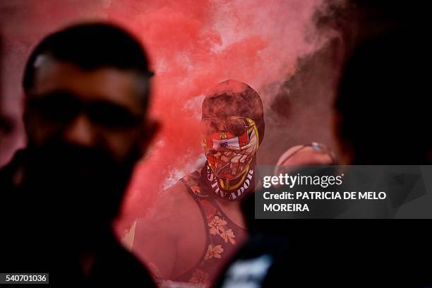 Masked Portuguese docker stands with red smoke around him during a demonstration against low wages, collective layoffs and insecurity at the...