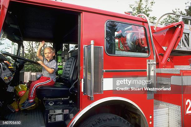 four year old boy in the driver's seat of a firetruck - fire engine stock pictures, royalty-free photos & images