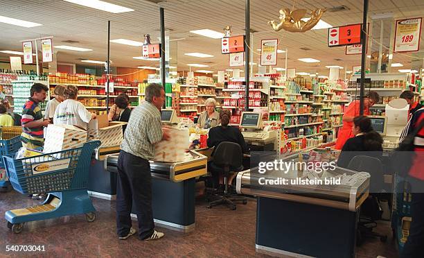 Einige Kunden packen im Kassenbereich eines spanischen Supermarktes in Jandia auf Fuerteventura-Süd ihre Waren ein. An einer Kasse steht ein blauer...