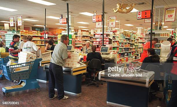 Einige Kunden packen im Kassenbereich eines spanischen Supermarktes in Jandia auf Fuerteventura-Süd ihre Waren ein. An einer Kasse steht ein blauer...
