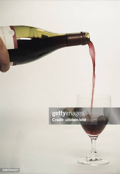 Aus einer Flasche wird Wein in ein Rotweinglas gegossen. Weinflasche. .