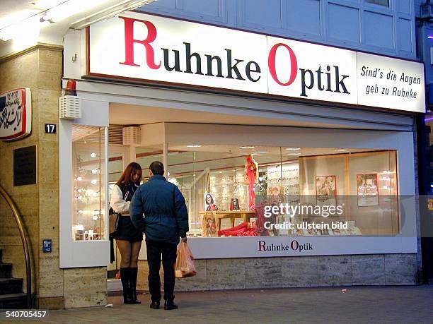 Eine Prostituierte steht vor einem Optikergeschäft am Steindamm im Hamburger Stadtteil St. Georg. Sie trägt Lederstiefel und einen Minirock. Ein Mann...