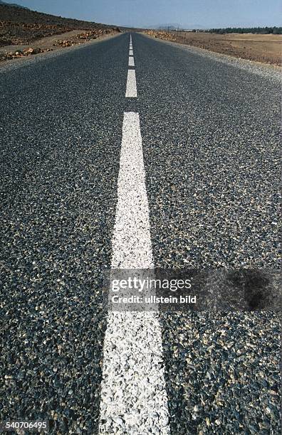 Endlose Landstraße mit Fahrbahnmarkierung in der Mitte. Undatiertes Foto.