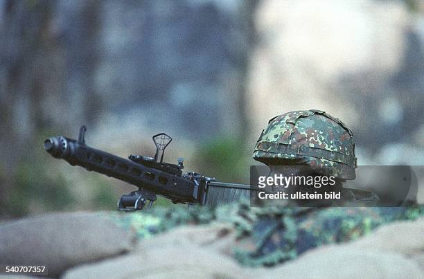 Flugabwehr mit Maschinengewehr, die Visiereinrichtung hochgeklappt: Ein Soldat mit Stahlhelm, das Gesicht mit Tarnfarbe abgedeckt, liegt in einer...